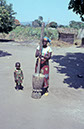 Bewohnerin (mit Kind) der Siedlung Mulindayifwa, Herstellung von Mehl